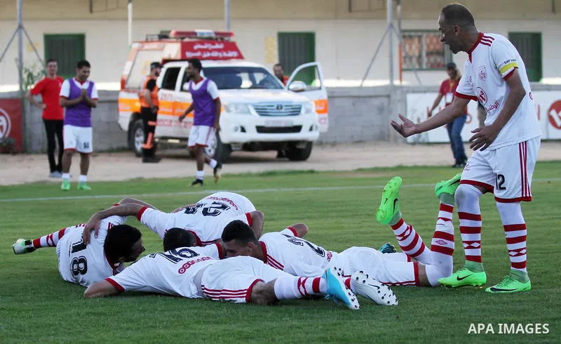 Palestinian players of Hilal al-Quds football club (in blue) compete with Palestinian players of Shabab Khan Younis football club (in white) during the first leg football match of the Palestine Cup final at the Palestine...