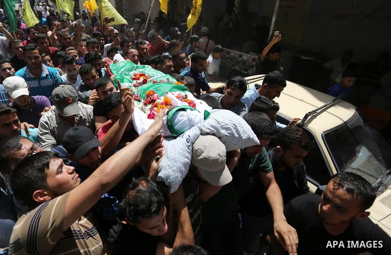 Mourners carry the body of Palestinian Mohammed Abu Daqqa, 24, who died of wounds he sustained during clashes with Israeli troops, during his funeral in Khan Younis in the southern of Gaza Strip on June 21, 2018. Photo b...