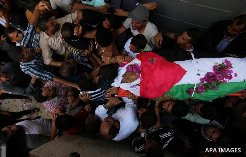 Mourners carry the body of Palestinian Osama Abu Khater, who died of wounds he sustained during clashes with Israeli troops, his funeral in Khan Younis in the southern Gaza Strip on June 24, 2018. Photo by Ashraf Amra