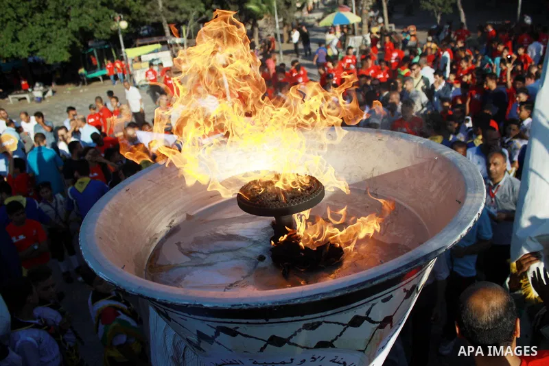 Palestinians light an urn marking the Palestinian Olympic Day, in Gaza city, on June 24, 2018. Photo by Bashar Zakri
