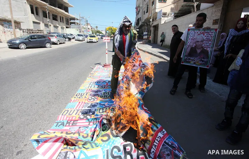 Palestinians burn an Israeli, British and U.S. flags during a protest to show solidarity with Palestinian prisoners held in Israeli jails, in front of Red cross office in Gaza city on June 25, 2018. Photo by Mahmoud Ajou...