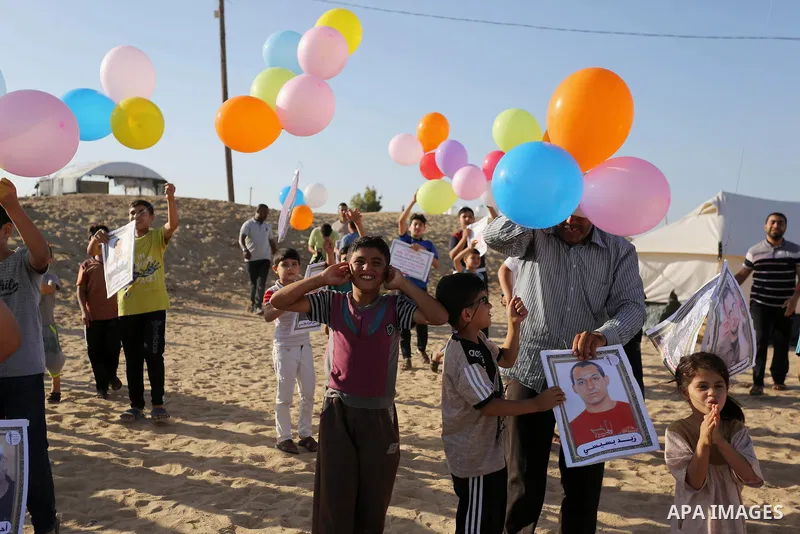 Palestinian children hold balloons before it be fly during a protest near tents at Gaza-Israel border, in Jabalia in the northern of Gaza Strip on June 27, 2018. Photo by Ashraf Amra