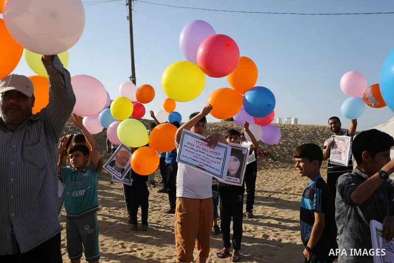 Palestinian children hold balloons before it be fly during a protest near tents at Gaza-Israel border, in Jabalia in the northern of Gaza Strip on June 27, 2018. Photo by Ashraf Amra