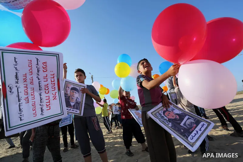 Palestinian children hold balloons before it be fly during a protest near tents at Gaza-Israel border, in Jabalia in the northern of Gaza Strip on June 27, 2018. Photo by Ashraf Amra