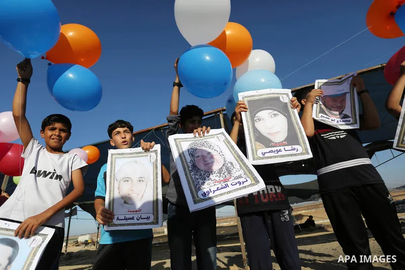 Palestinian children hold balloons before it be fly during a protest near tents at Gaza-Israel border, in Jabalia in the northern of Gaza Strip on June 27, 2018. Photo by Ashraf Amra