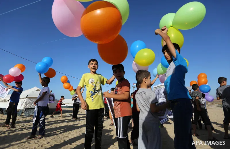 Palestinian children hold balloons before it be fly during a protest near tents at Gaza-Israel border, in Jabalia in the northern of Gaza Strip on June 27, 2018. Photo by Ashraf Amra