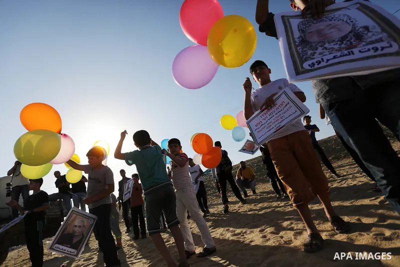 Palestinian children hold balloons before it be fly during a protest near tents at Gaza-Israel border, in Jabalia in the northern of Gaza Strip on June 27, 2018. Photo by Ashraf Amra