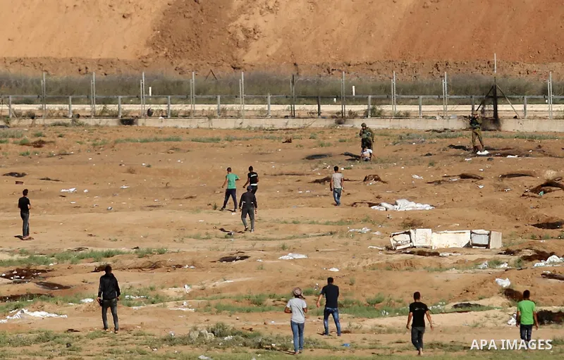 Israeli soldiers detains a wounded Palestinian protester at Gaza-Israel border, in Jabalia in the northern of Gaza Strip on June 27, 2018. Photo by Ashraf Amra