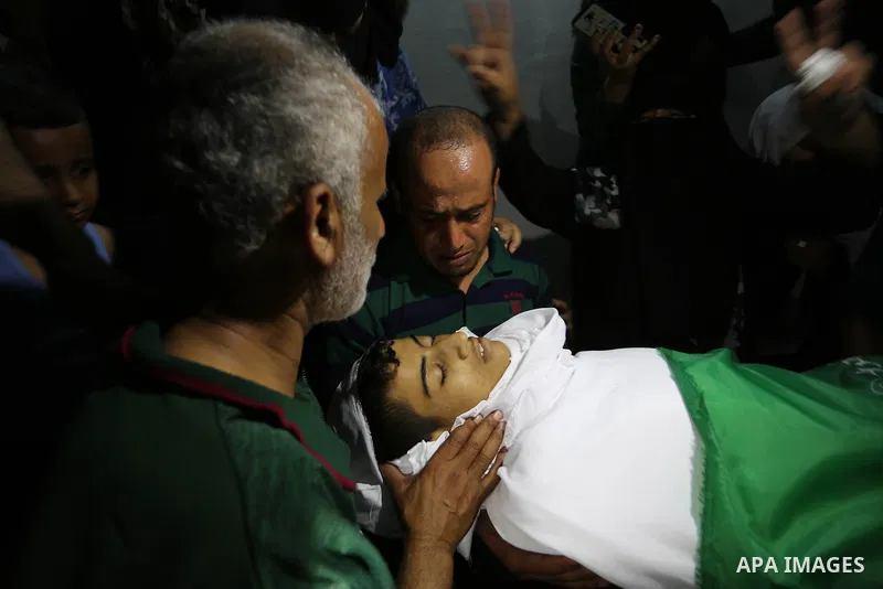 Relatives of Palestinian Abdul Fattah Abu Azoum 17, who was killed in Israeli tank fire earlier in the day, at the Israel-Gaza border, mourn over his body during his funeral in Rafah in the southern Gaza strip on June 28...