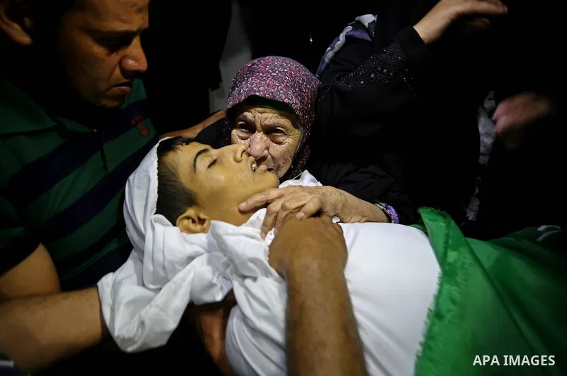 Relatives of Palestinian Abdul Fattah Abu Azoum 17, who was killed in Israeli tank fire earlier in the day, at the Israel-Gaza border, mourn over his body during his funeral in Rafah in the southern Gaza strip on June 28...