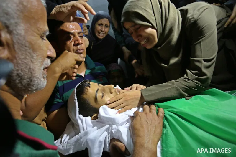 Relatives of Palestinian Abdul Fattah Abu Azoum 17, who was killed in Israeli tank fire earlier in the day, at the Israel-Gaza border, mourn over his body during his funeral in Rafah in the southern Gaza strip on June 28...