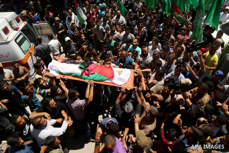 Mourners carry the body of 14-year-old Palestinian boy Yasser Abu Al-Naja, who was killed by Israeli troops during clashes in tents protest where Palestinian demand the right to return to their homeland at the Israel-Gaz...