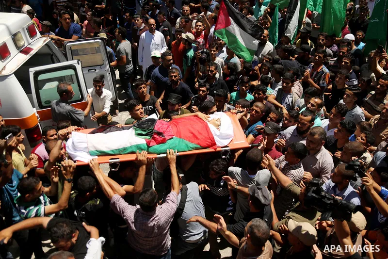 Mourners carry the body of 14-year-old Palestinian boy Yasser Abu Al-Naja, who was killed by Israeli troops during clashes in tents protest where Palestinian demand the right to return to their homeland at the Israel-Gaz...