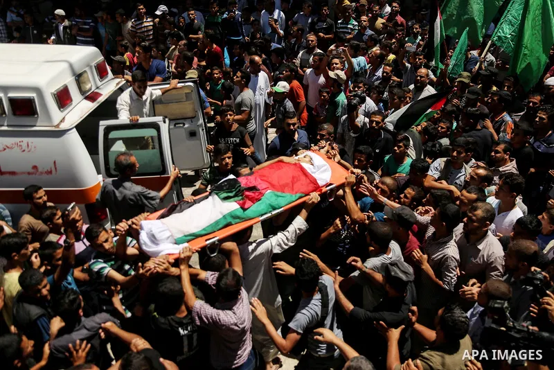 Mourners carry the body of 14-year-old Palestinian boy Yasser Abu Al-Naja, who was killed by Israeli troops during clashes in tents protest where Palestinian demand the right to return to their homeland at the Israel-Gaz...