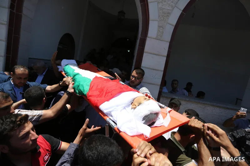 Mourners carry the body of 14-year-old Palestinian boy Yasser Abu Al-Naja, who was killed by Israeli troops during clashes in tents protest where Palestinian demand the right to return to their homeland at the Israel-Gaz...