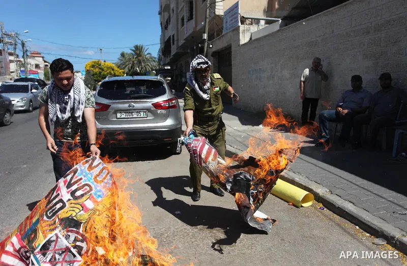 Palestinians burn an Israeli, British and U.S. flags during a protest to show solidarity with Palestinian prisoners held in Israeli jails, in front of Red cross office in Gaza city on July 2, 2018. Photo by Mahmoud Ajour