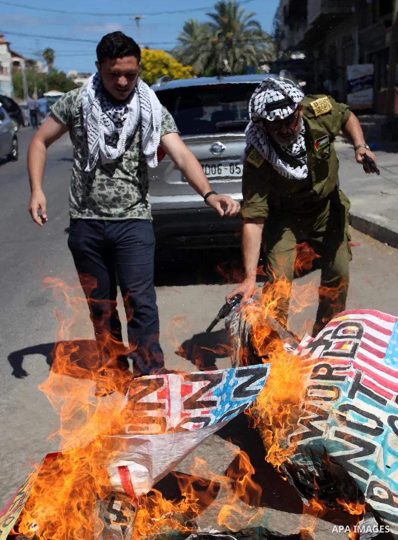 Palestinians burn an Israeli, British and U.S. flags during a protest to show solidarity with Palestinian prisoners held in Israeli jails, in front of Red cross office in Gaza city on July 2, 2018. Photo by Mahmoud Ajour