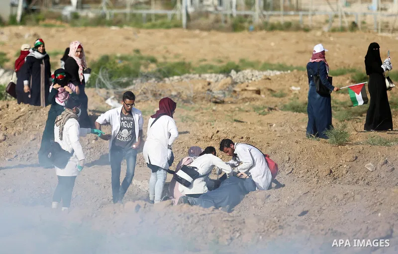 Palestinian medics help a female protester during a protest by Palestinian women where Palestinians demand the right to return to their homeland along the border with Israel east of Gaza City on July 3, 2018. Photo by As...