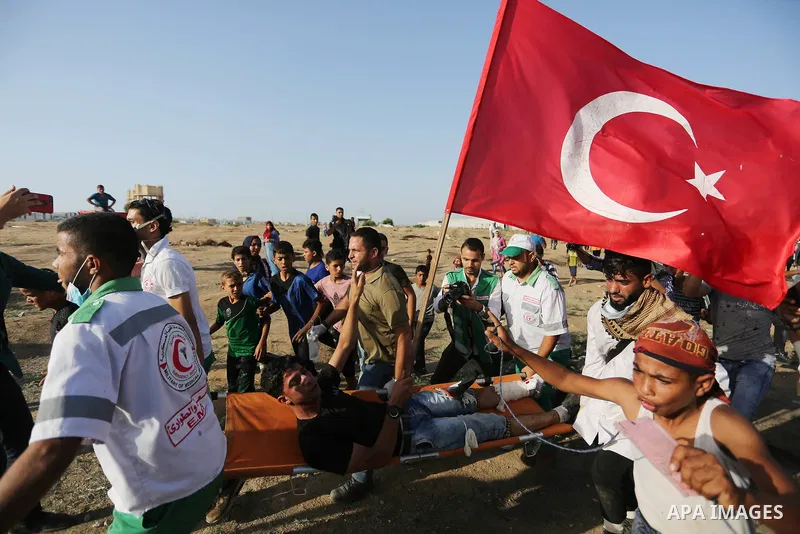 Palestinian Paramedics carry away an injured protester during a protest by Palestinian women where Palestinians demand the right to return to their homeland along the border with Israel east of Gaza City on July 3, 2018....