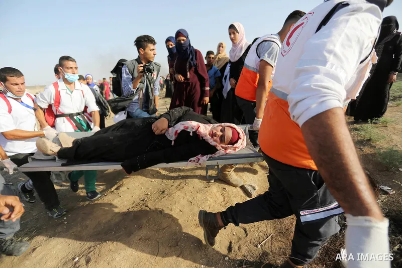 Palestinian Paramedics carry away an injured female protester during a protest by Palestinian women where Palestinians demand the right to return to their homeland along the border with Israel east of Gaza City on July 3...