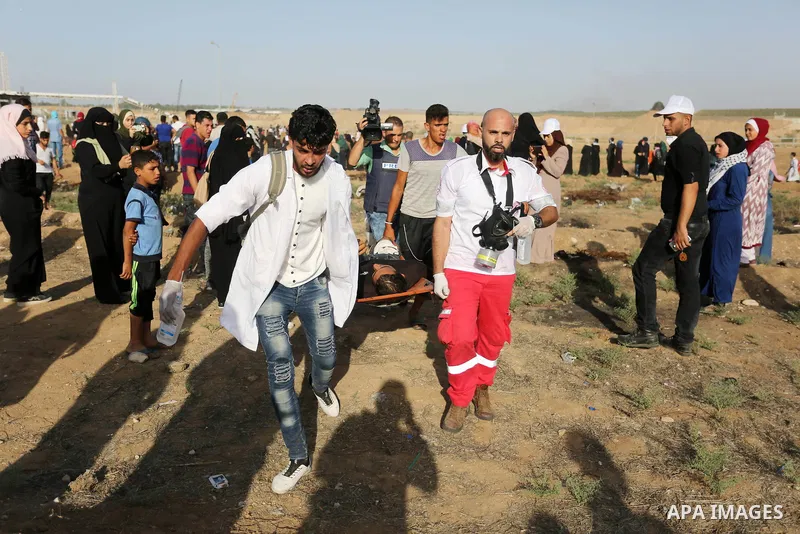 Palestinian Paramedics carry away an injured protester during a protest by Palestinian women where Palestinians demand the right to return to their homeland along the border with Israel east of Gaza City on July 3, 2018....