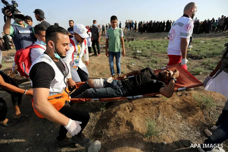 Palestinian Paramedics carry away an injured protester during a protest by Palestinian women where Palestinians demand the right to return to their homeland along the border with Israel east of Gaza City on July 3, 2018....