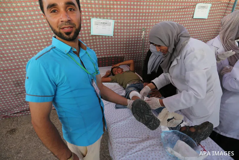 Palestinian Paramedics provide treatment for an injured protester during a protest by Palestinian women where Palestinians demand the right to return to their homeland along the border with Israel east of Gaza City on Ju...