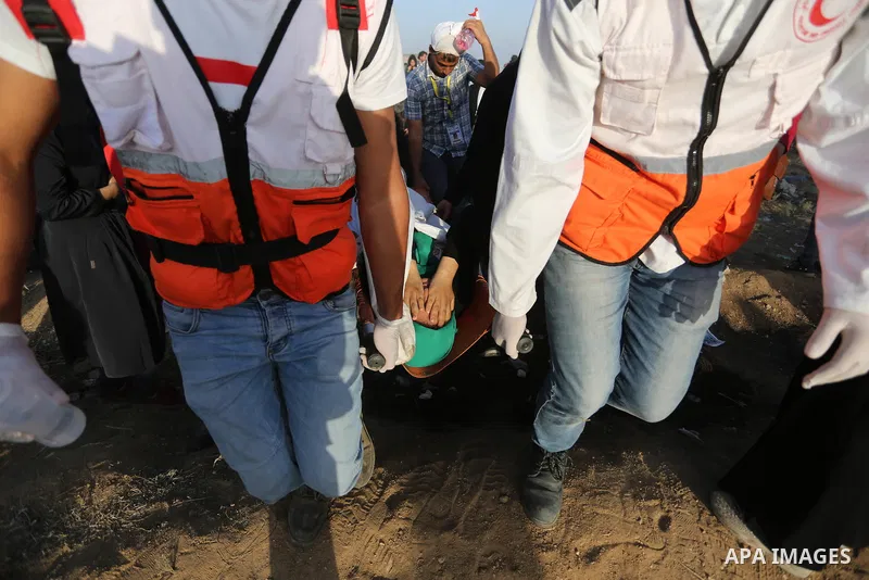 Palestinian Paramedics carry away an injured female protester during a protest by Palestinian women where Palestinians demand the right to return to their homeland along the border with Israel east of Gaza City on July 3...