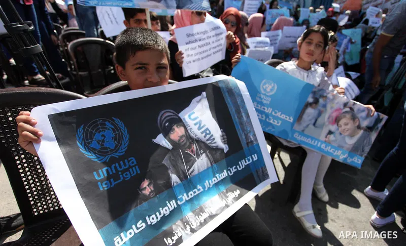 Palestinians hold banners during in a protest against a U.S. decision to cut aid, in front of the headquarters United Nations Relief and Works Agency (UNRWA), in Gaza City on July 4, 2018. Photo by Mahmoud Ajour