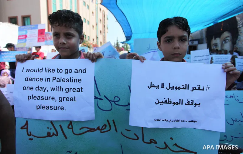 Palestinians hold banners during in a protest against a U.S. decision to cut aid, in front of the headquarters United Nations Relief and Works Agency (UNRWA), in Gaza City on July 4, 2018. Photo by Mahmoud Ajour