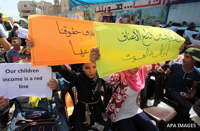 Palestinians hold banners during in a protest against a U.S. decision to cut aid, in front of the headquarters United Nations Relief and Works Agency (UNRWA), in Gaza City on July 4, 2018. Photo by Mahmoud Ajour