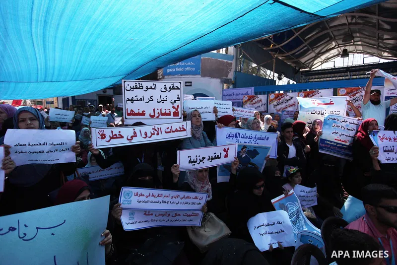 Palestinians hold banners during in a protest against a U.S. decision to cut aid, in front of the headquarters United Nations Relief and Works Agency (UNRWA), in Gaza City on July 4, 2018. Photo by Mahmoud Ajour