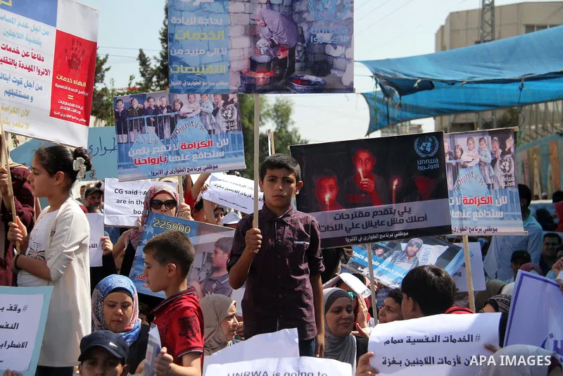 Palestinians hold banners during in a protest against a U.S. decision to cut aid, in front of the headquarters United Nations Relief and Works Agency (UNRWA), in Gaza City on July 4, 2018. Photo by Mahmoud Ajour