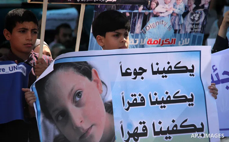Palestinians hold banners during in a protest against a U.S. decision to cut aid, in front of the headquarters United Nations Relief and Works Agency (UNRWA), in Gaza City on July 4, 2018. Photo by Mahmoud Ajour