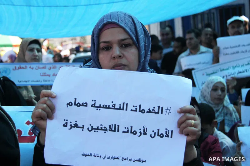 Palestinians hold banners during in a protest against a U.S. decision to cut aid, in front of the headquarters United Nations Relief and Works Agency (UNRWA), in Gaza City on July 4, 2018. Photo by Mahmoud Ajour