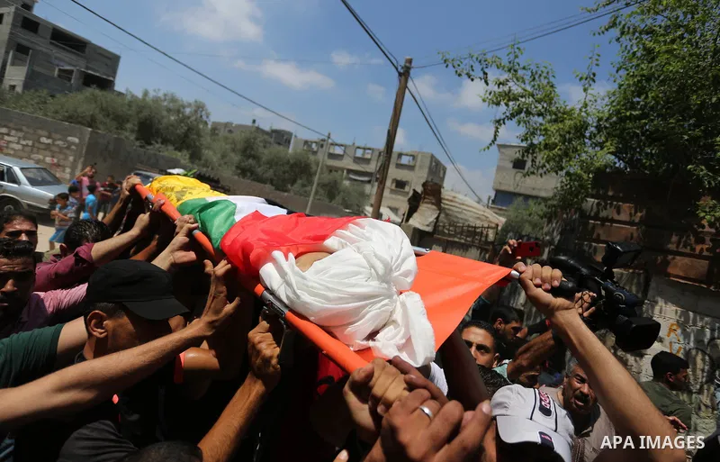Mourners carry the body of Palestinian Mahmoud al-Ghrabli ,16, who died of wounds he sustained during clashes with Israeli troops, his funeral in Gaza city on July 5, 2018. Photo by Ashraf Amra