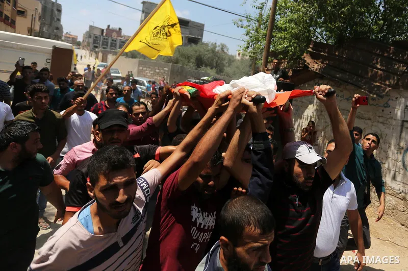 Mourners carry the body of Palestinian Mahmoud al-Ghrabli ,16, who died of wounds he sustained during clashes with Israeli troops, his funeral in Gaza city on July 5, 2018. Photo by Ashraf Amra