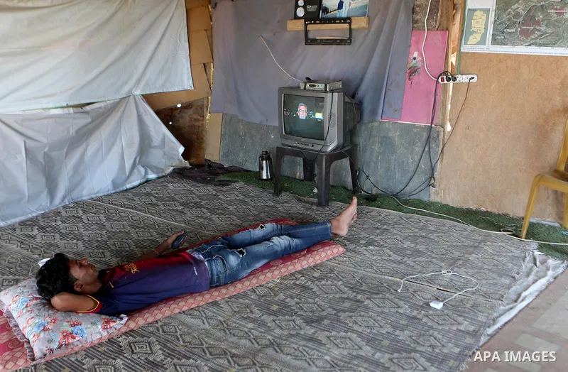 A Palestinian man watches TV at his dwelling at the Palestinian Bedouin village of Khan al-Ahmar, east of Jerusalem in the occupied West Bank on July 6, 2018. Israel's Supreme Court has temporarily blocked the demolition...