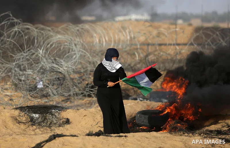 A Palestinian woman holds the national flag during clashes with Israeli troops in tents protest where Palestinian demand the right to return to their homeland at the Israel-Gaza border, in Khan Younis in the southern Gaz...