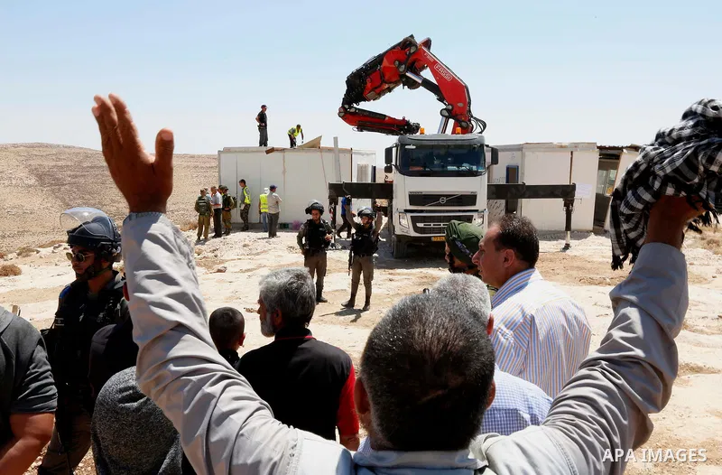 Palestinian protesters argue with Israeli border police as the Israeli army removes containers used as a school, near the West Bank city of Hebron on July 11, 2018. Photo by Wisam Hashlamoun