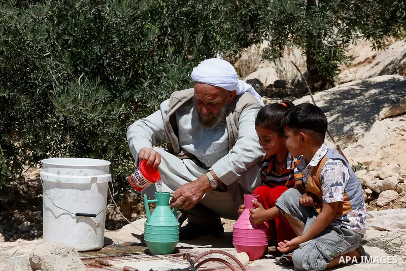 A Palestinian man fills water outside the cave they use as their home, outskirts of the West Bank village of Mufagra, near Hebron on July 10, 2018. Photo by Wisam Hashlamoun