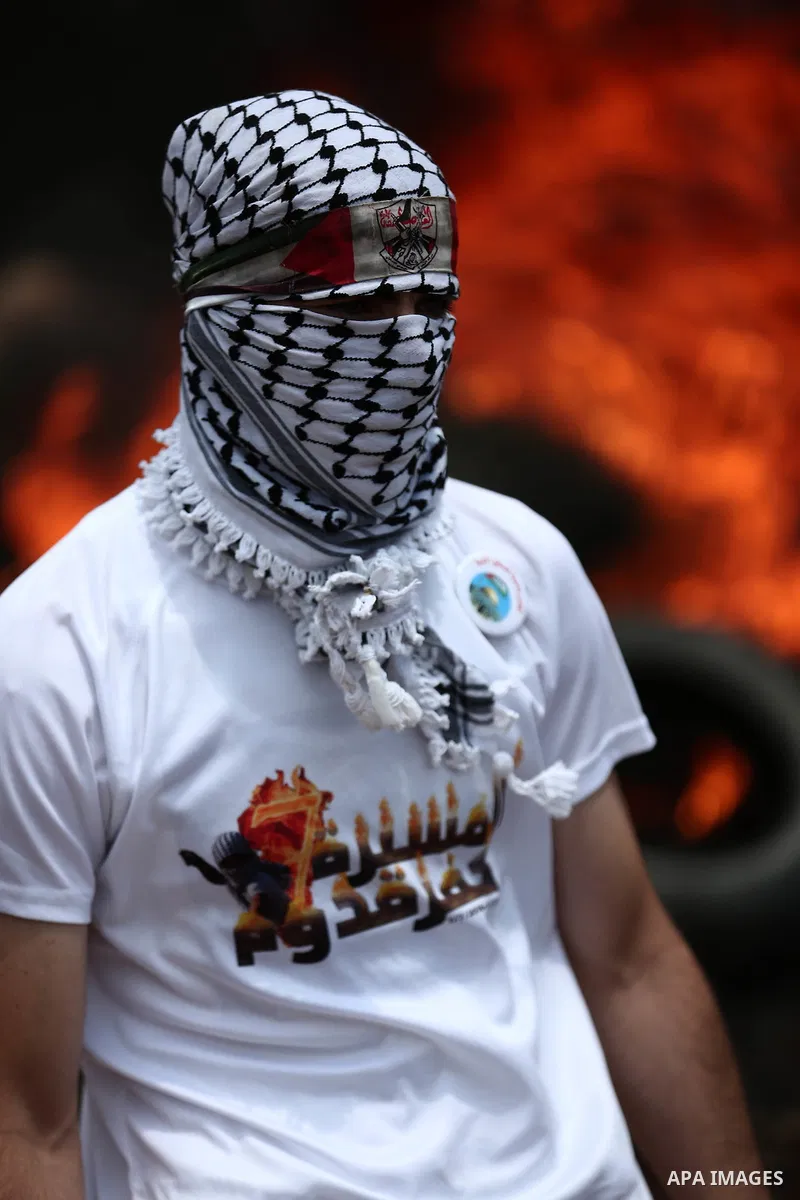 A masked Palestinian protester looks on during clashes with Israeli troops following a demonstration against the expropriation of Palestinian land by Israel in the village of Kfar Qaddum, near Nablus, in the occupied Wes...