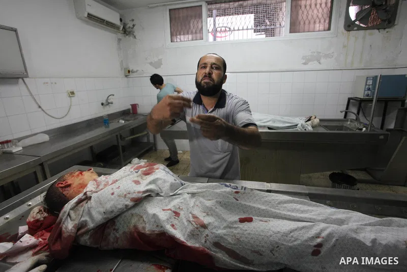 A Relative mourns over the body of 15-year-old Ameer al-Namara, who was killed during an Israeli air strike on Gaza city, at al-Shifa hospital, 14 July 2018. At least two Palestinians were killed after an Israeli air str...