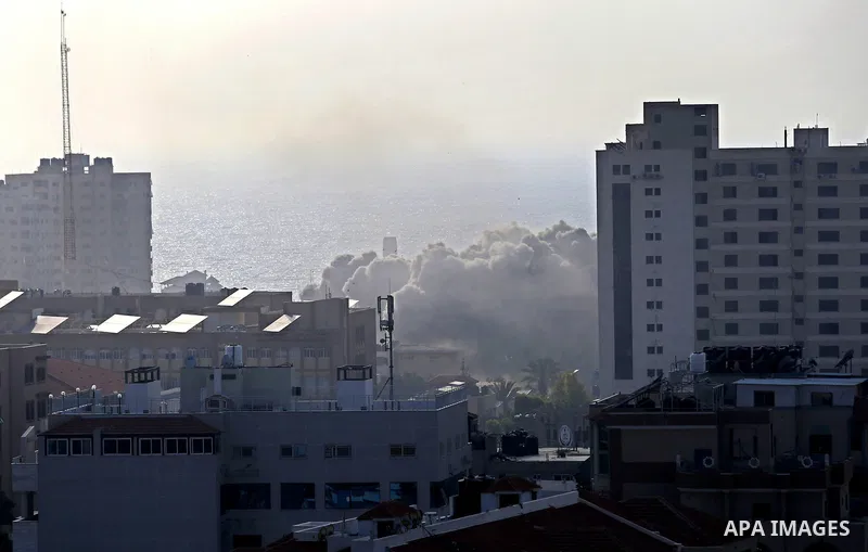 Smoke rises above buildings during an Israeli air strike on Gaza City on July 14, 2018. At least two Palestinians were killed after an Israeli air strike hit an empty building in Gaza City. Photo by Ashraf Amra