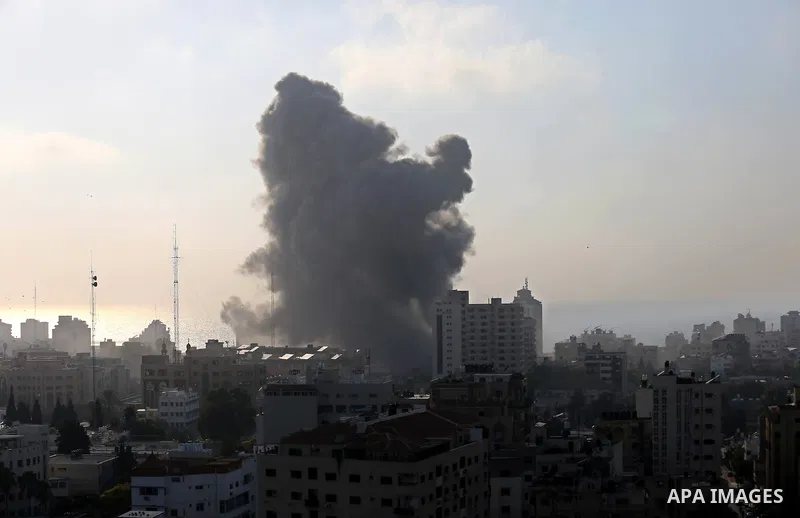 Smoke rises above buildings during an Israeli air strike on Gaza City on July 14, 2018. At least two Palestinians were killed after an Israeli air strike hit an empty building in Gaza City. Photo by Ashraf Amra