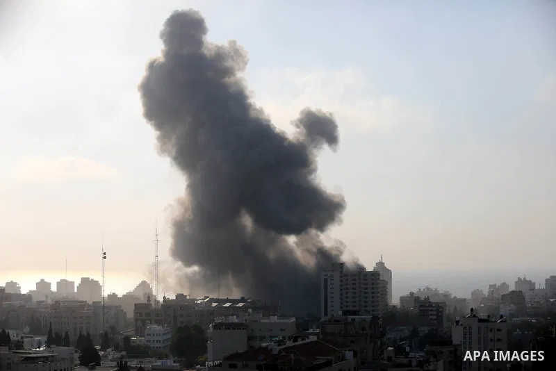 Smoke rises above buildings during an Israeli air strike on Gaza City on July 14, 2018. At least two Palestinians were killed after an Israeli air strike hit an empty building in Gaza City. Photo by Ashraf Amra