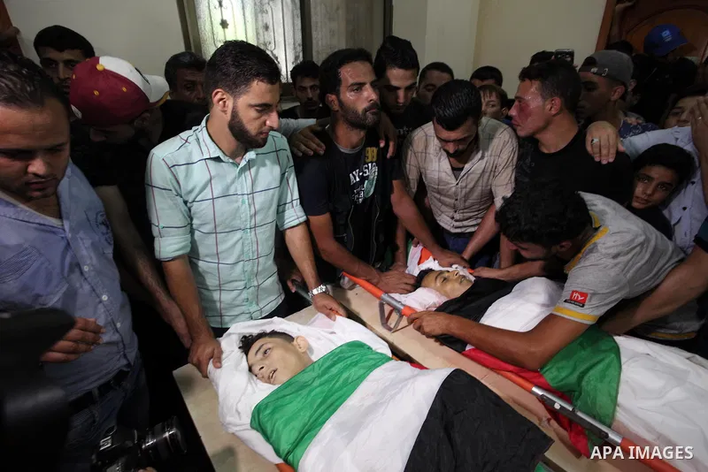 Relatives of two Palestinians, who were killed in an Israeli air strike, mourn over their bodies during their funeral at a mosque in Gaza city on July 15, 2018. Photo by Mahmoud Ajour