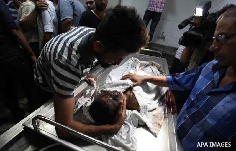 Relatives of Palestinian Louay Hassan ,13, who was killed in an unexplained explosion mourn over his body at morgue in al-shifa hospital, in Gaza city on July 15, 2018. Photo by Mahmoud Ajour