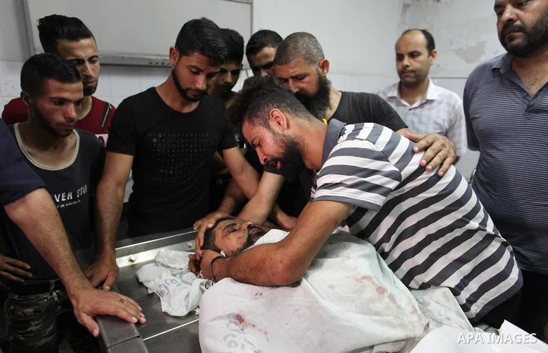 Relatives of Palestinian Ahmed Hassan ,35, who was killed in an unexplained explosion mourn over his body at morgue in al-shifa hospital, in Gaza city on July 15, 2018. Photo by Mahmoud Ajour