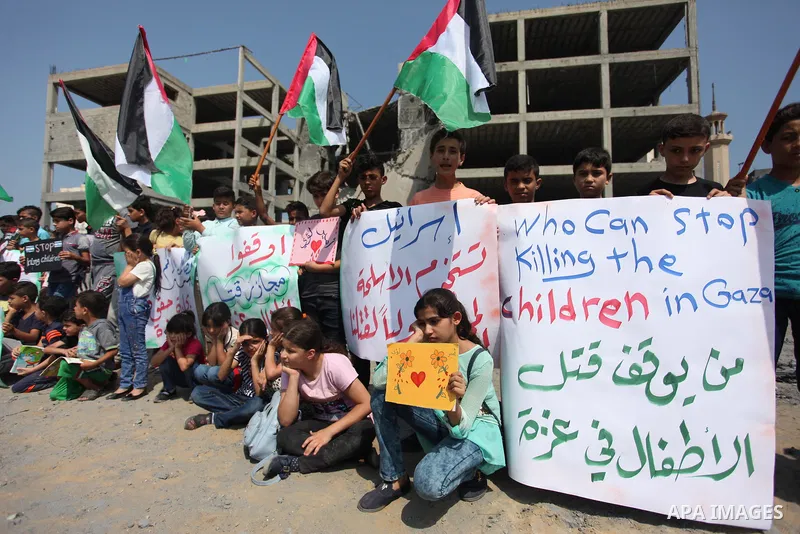 Palestinian children take part in a protest against the killing of Palestinian teenagers Louay Kahil and Amir Al-Namara, who were killed in an Israeli air strike, in front of the building that was damaged in an Israeli a...